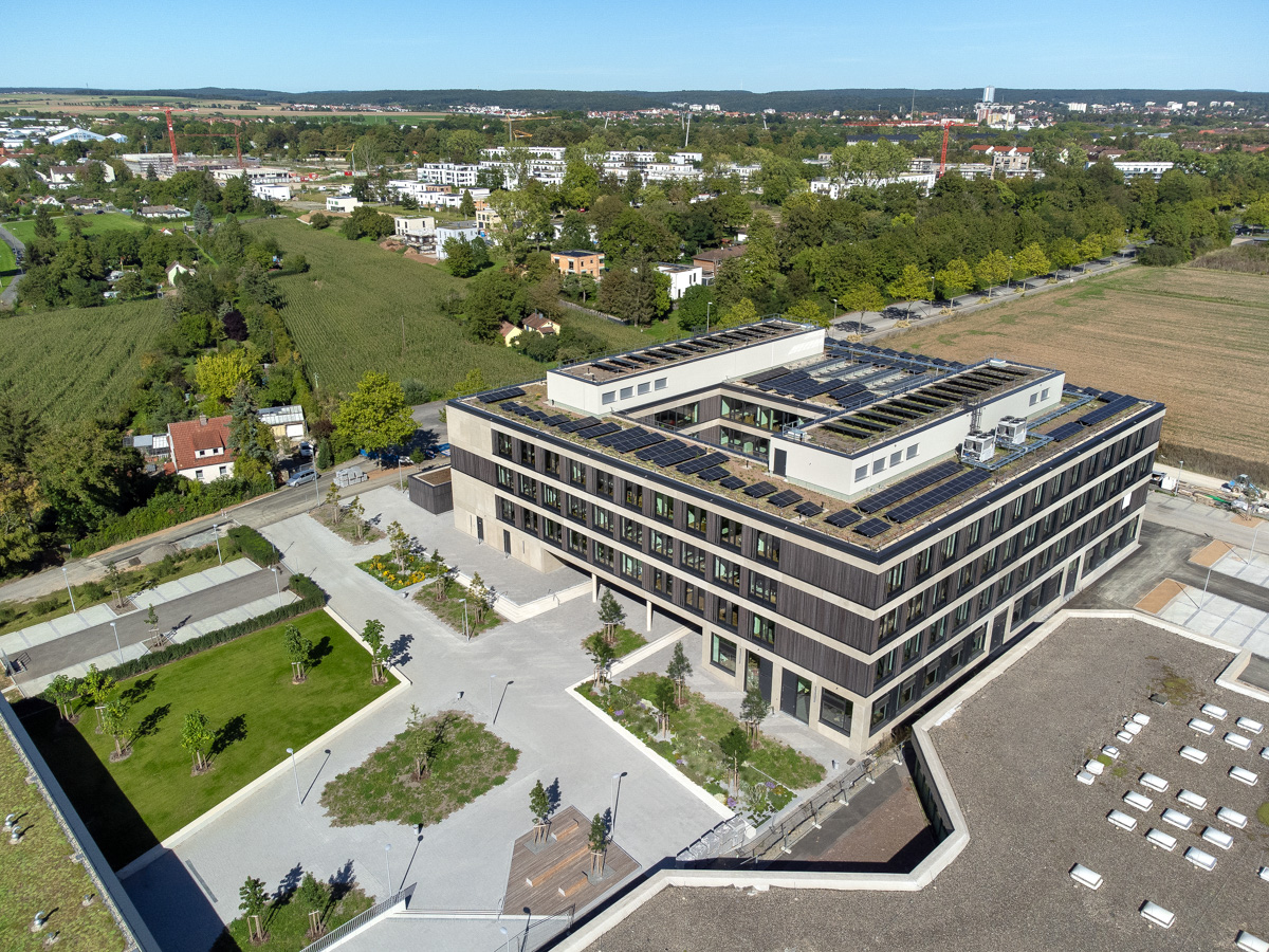 Luftbild vom quadratischen Kubus des Berufsschulzentrums mit umgebender Landschaft und Pausenhof