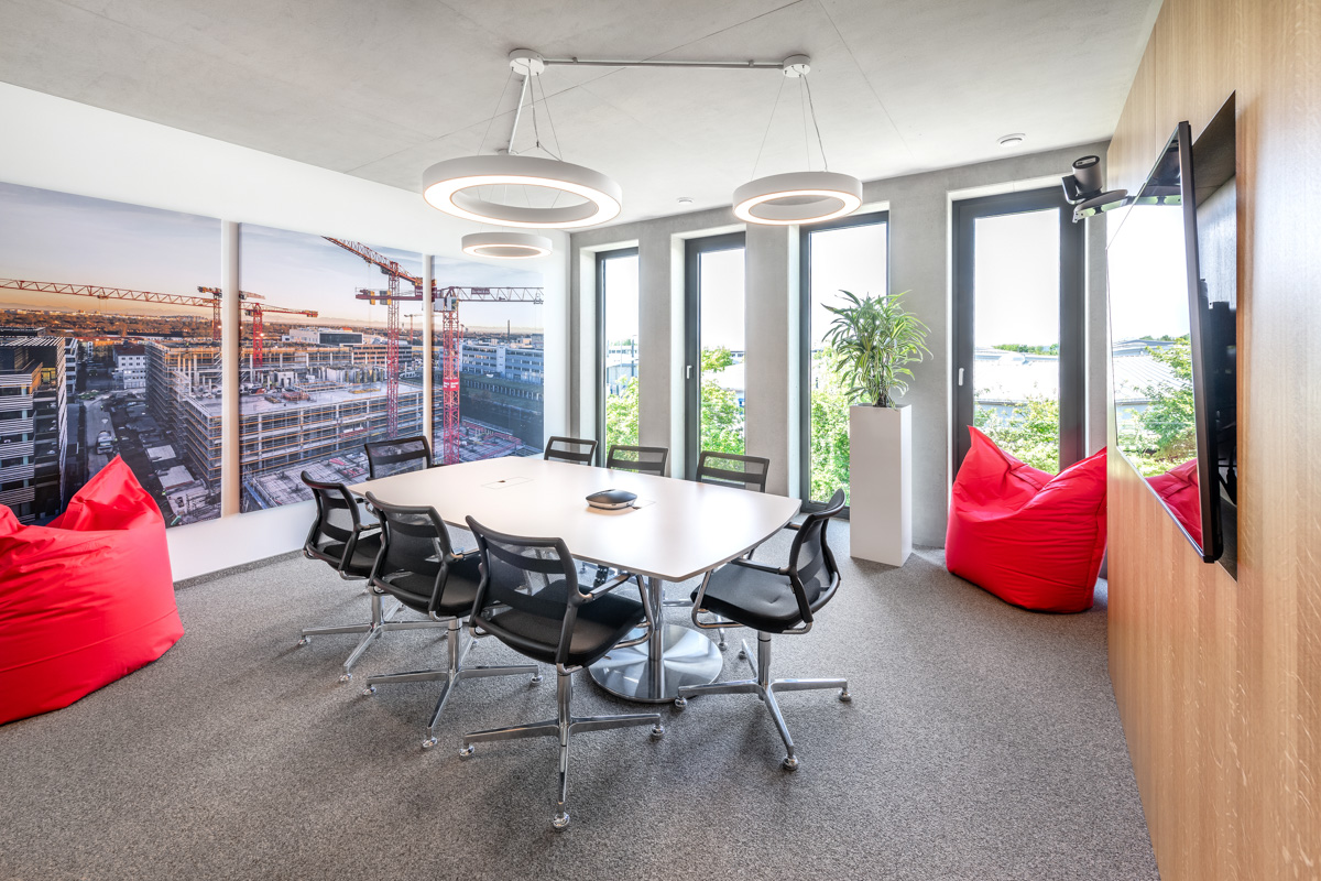 Besprechungsraum mit roten Sitzsäcken und einem großen Baustellenbild an der Wand