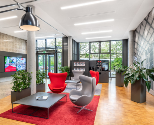 Wartebereich und Meetigpoint mit roten und grauen Designmöbeln und Glasfassade
