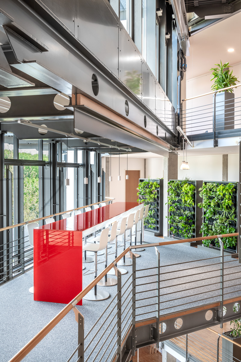 Meetingpoint mit langem roten Tisch auf einer frei schwebenden Galerie im Bürogebäude